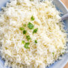 Baked coconut rice topped with cilantro in a blue serving bowl.