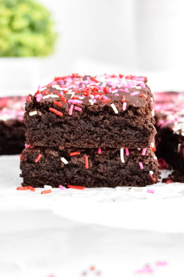 Valentine's Day brownies covered in red, pink and white sprinkles stacked on top of each other.