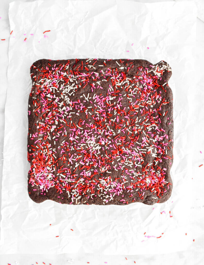 Baked Valentine's Day Brownies covered in sprinkles on parchment paper.