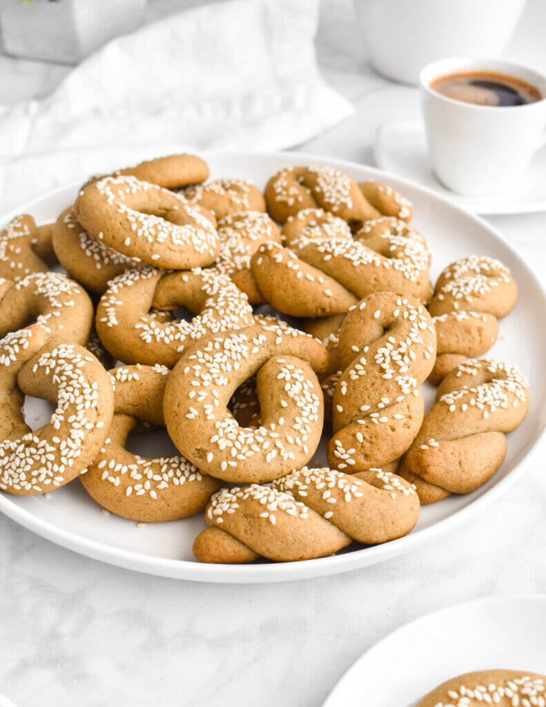 Closeup of a plate of circular and twisted koulouraki-shaped olive oil cookies.
