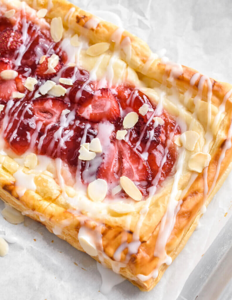 Close up of a baked strawberry cream cheese danish set on parchment paper.