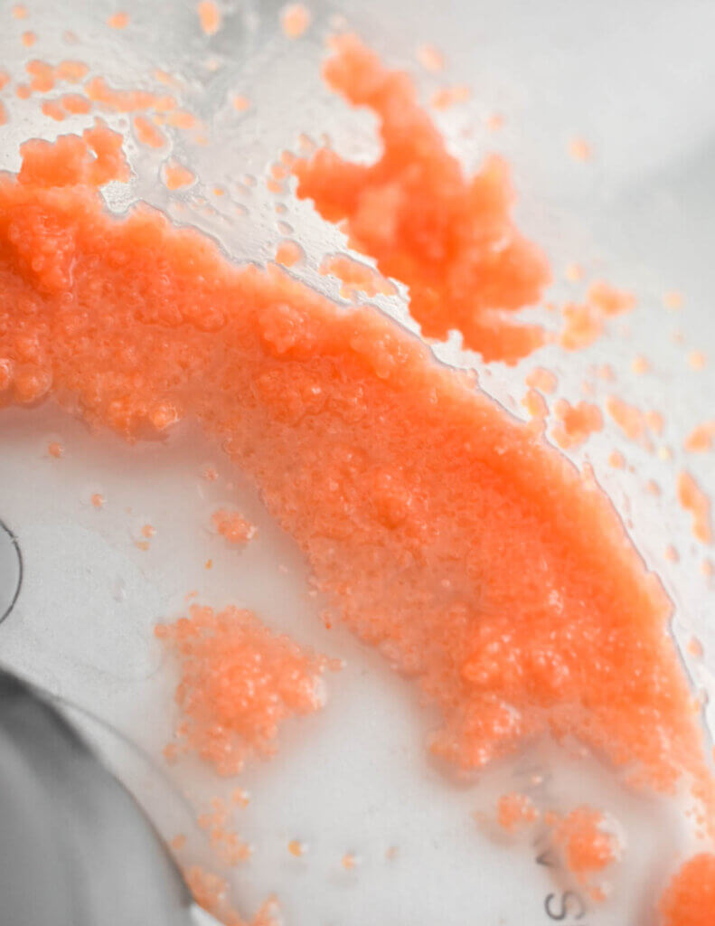 Spoonfuls of tarama (red carp caviar) processed with some water in a food processor bowl.