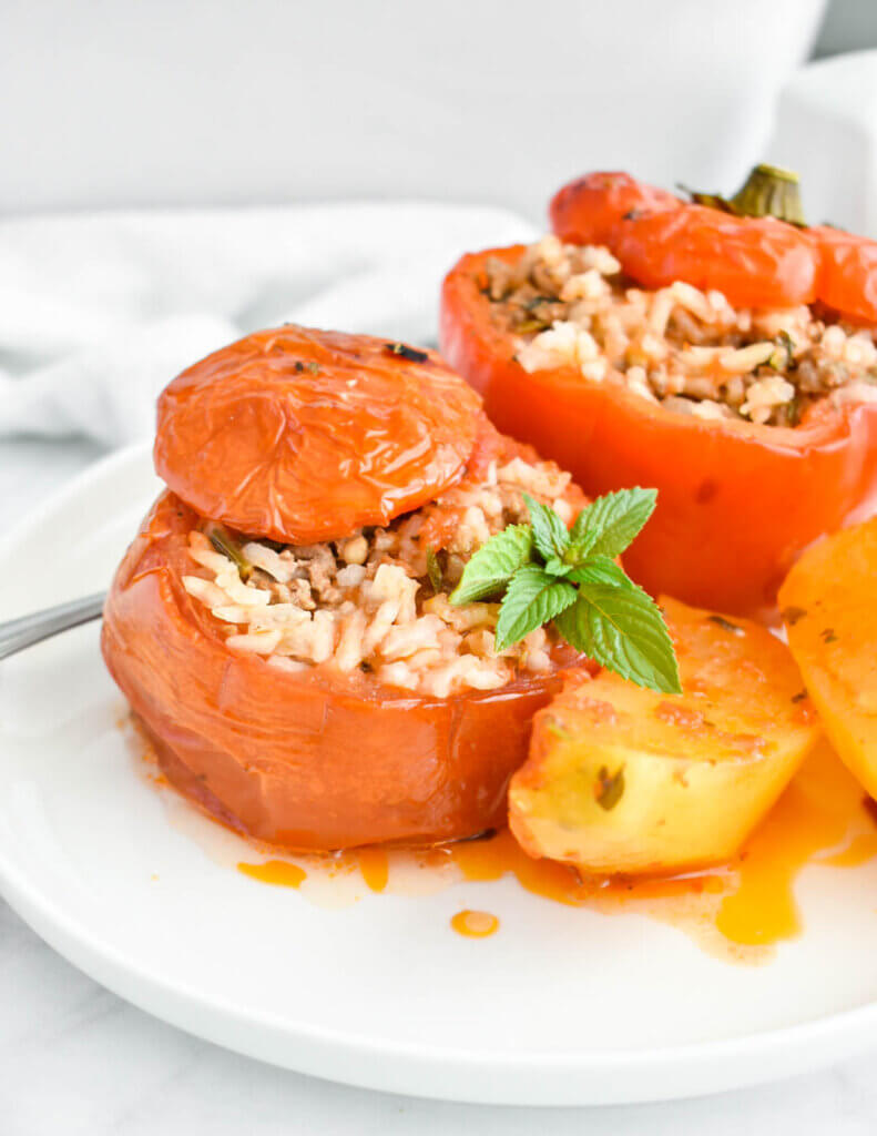 Closeup of a baked tomato stuffed with ground beef and rice and topped with fresh basil.
