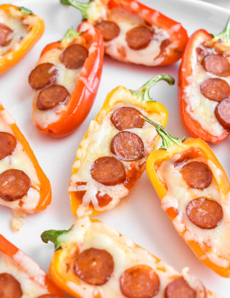 Pepperoni and cheese stuffed mini peppers on a baking sheet.