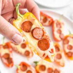 Closeup of a person holding up a pizza stuffed mini pepper.