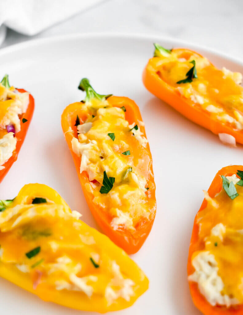 Closeup of a tuna stuffed mini pepper on a plate with other peppers.