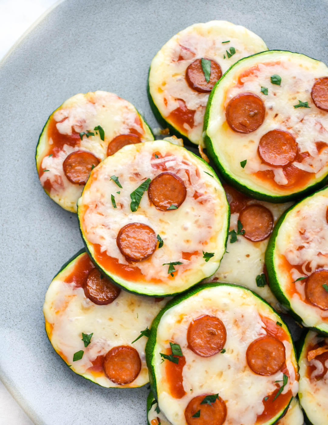 Zucchini Pizza Bites topped with pepperoni on a blue platter.