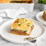 A slice of moussaka topped with fresh parsley.