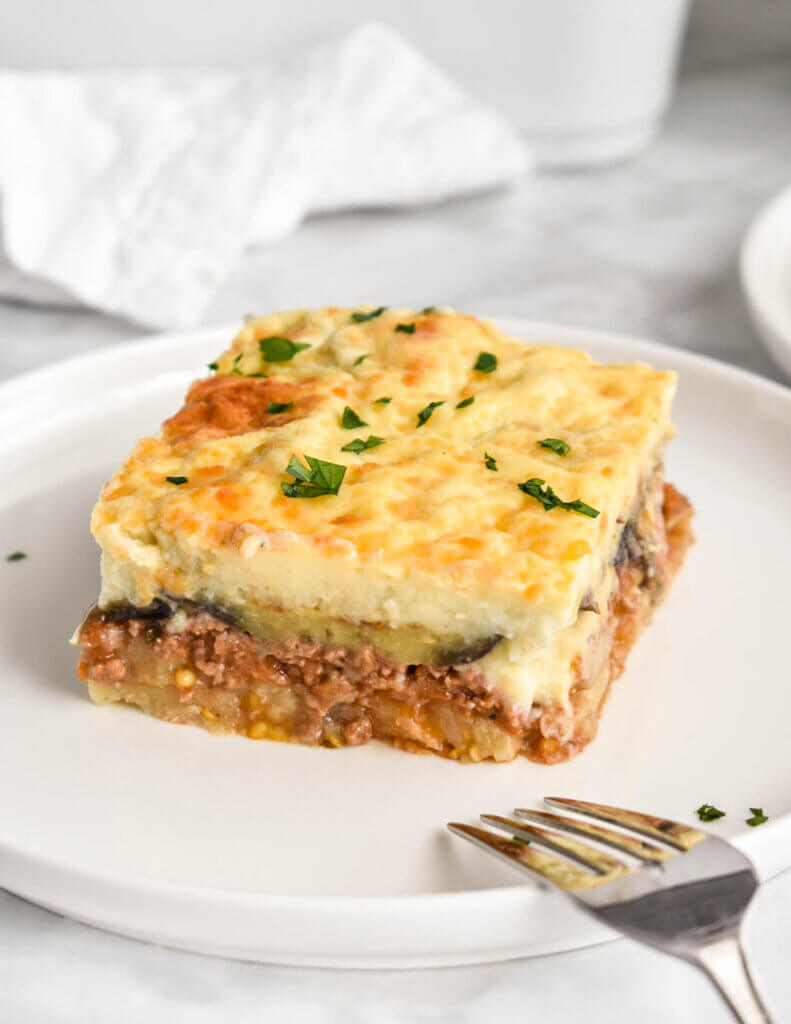 A slice of moussaka on a white plate.