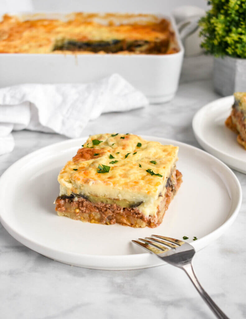 A slice of moussaka topped with fresh parsley.