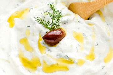 Tzatziki sauce drizzled with olive oil and topped with fresh dill and a kalamata olive.