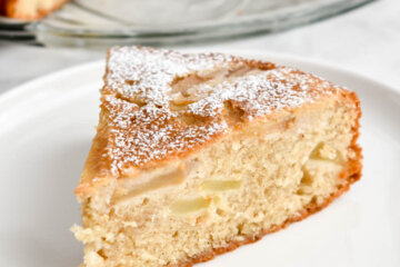 A slice of apple cake or milopita on a white plate.