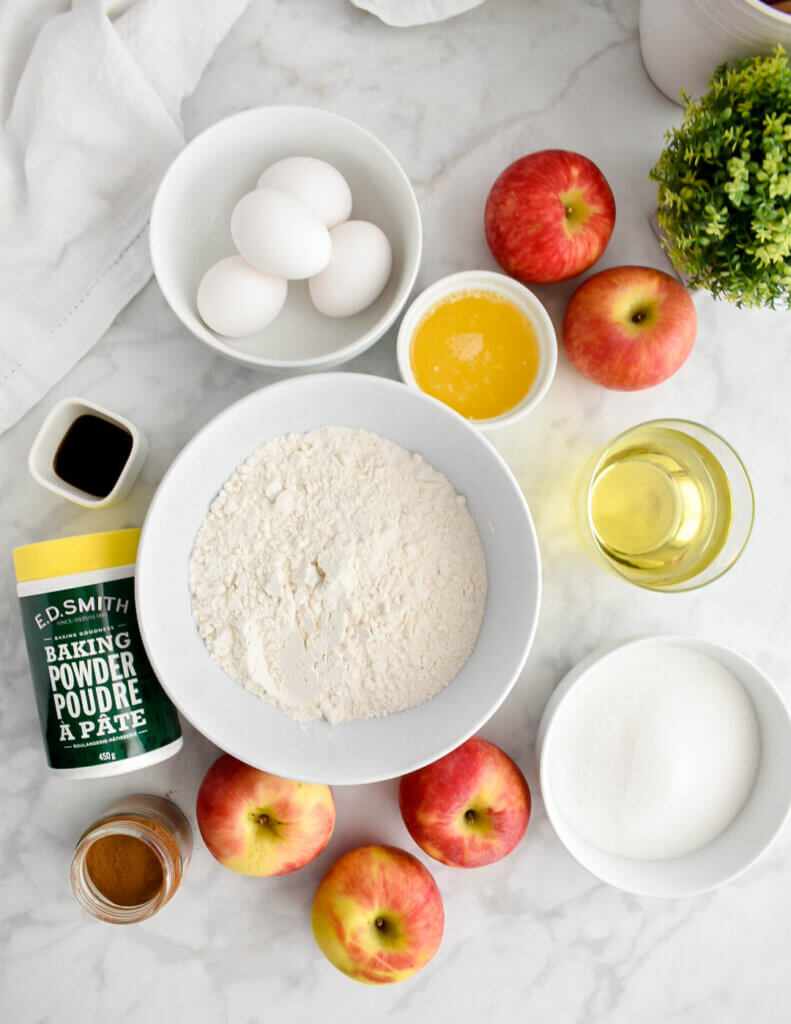 The ingredients for apple cake on a marble countertop.