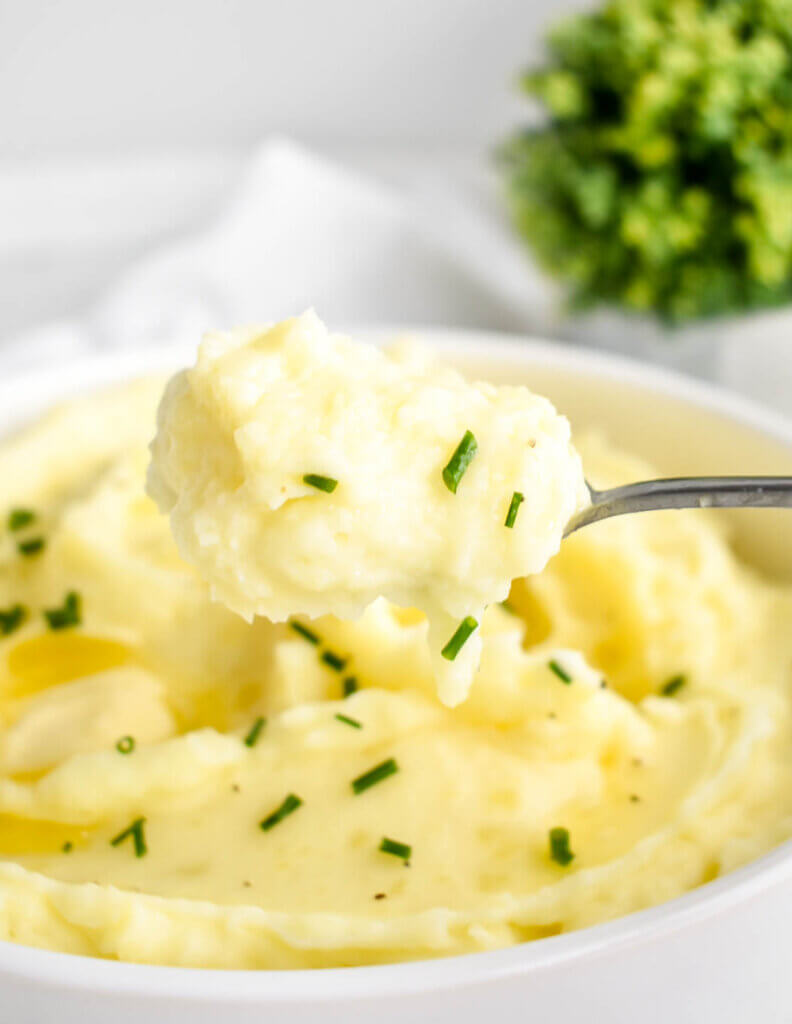 A spoonful of fluffy whipped potatoes sprinkled with chives.