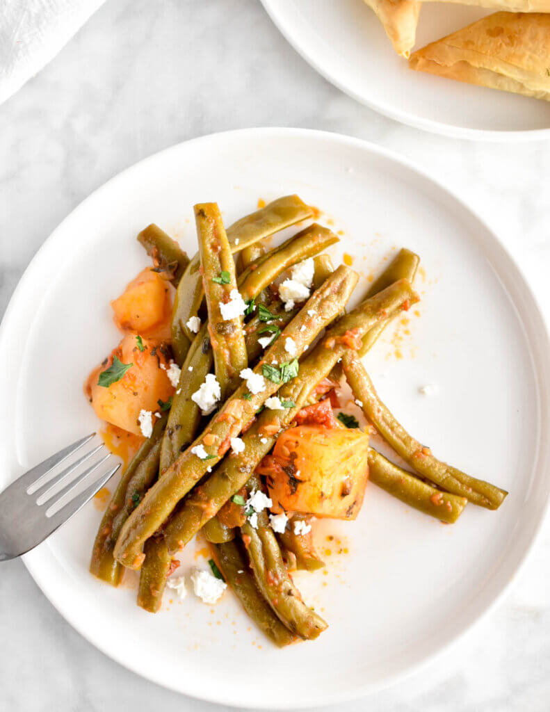 A plate of slow cooker greek green beans topped with crumbled feta.