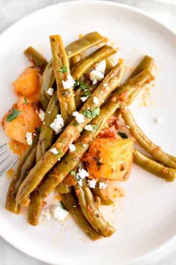 Slow Cooker Greek Green Beans on a plate topped with crumbled feta.