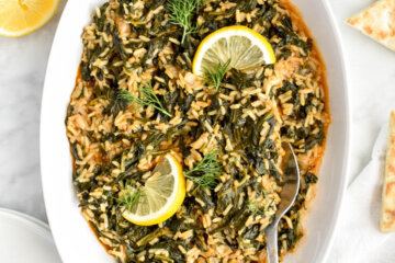Spanakorizo (Greek Spinach and Rice) in an oval serving platter topped with lemon wedges.