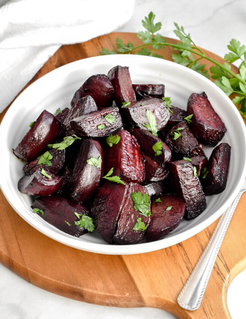 A bowl of roasted beets topped with fresh parsley.