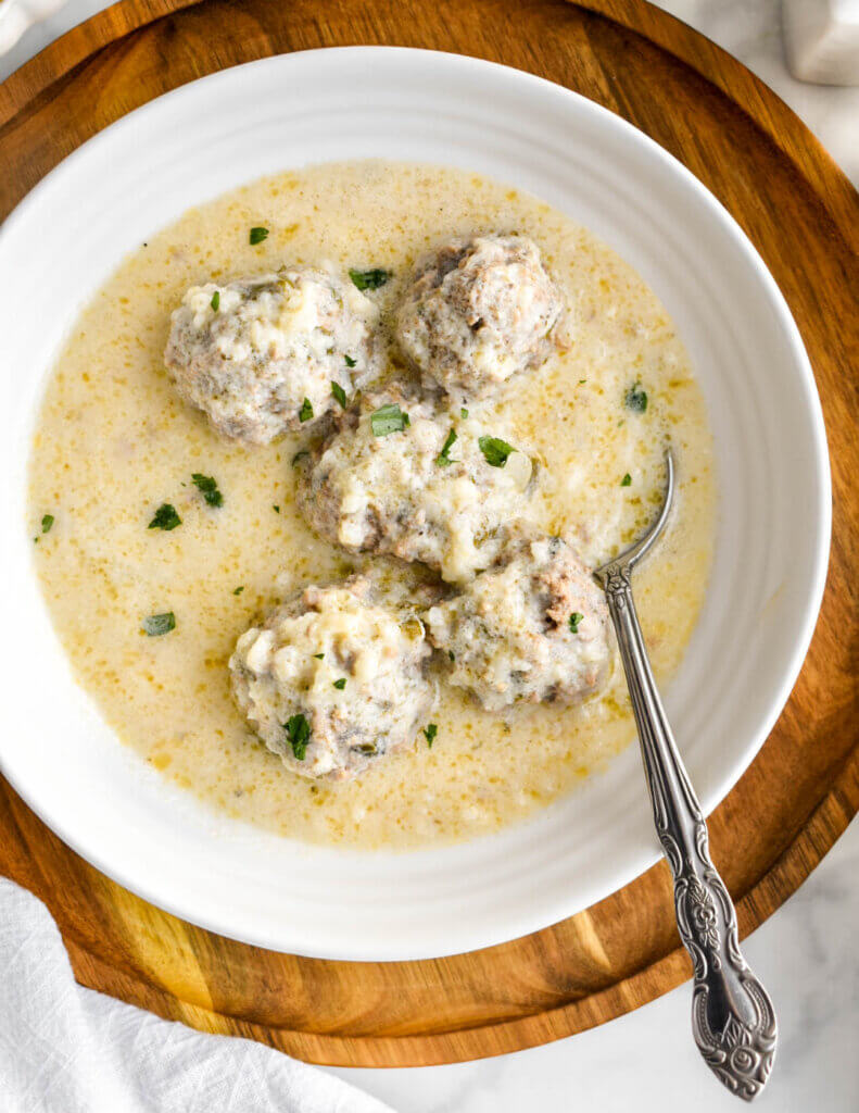 Closeup of meatballs in a bowl of youvarlakia soup with avgolemono sauce.