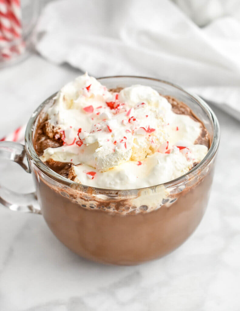 Closeup of a Starbucks copycat peppermint mocha in a clear mug topped with whipped crem and crushed candy cane.