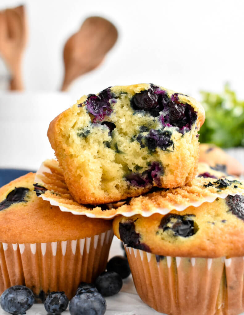 A bitten Buttermilk Blueberry Muffin showing the tender crumb and juicy blueberries inside.