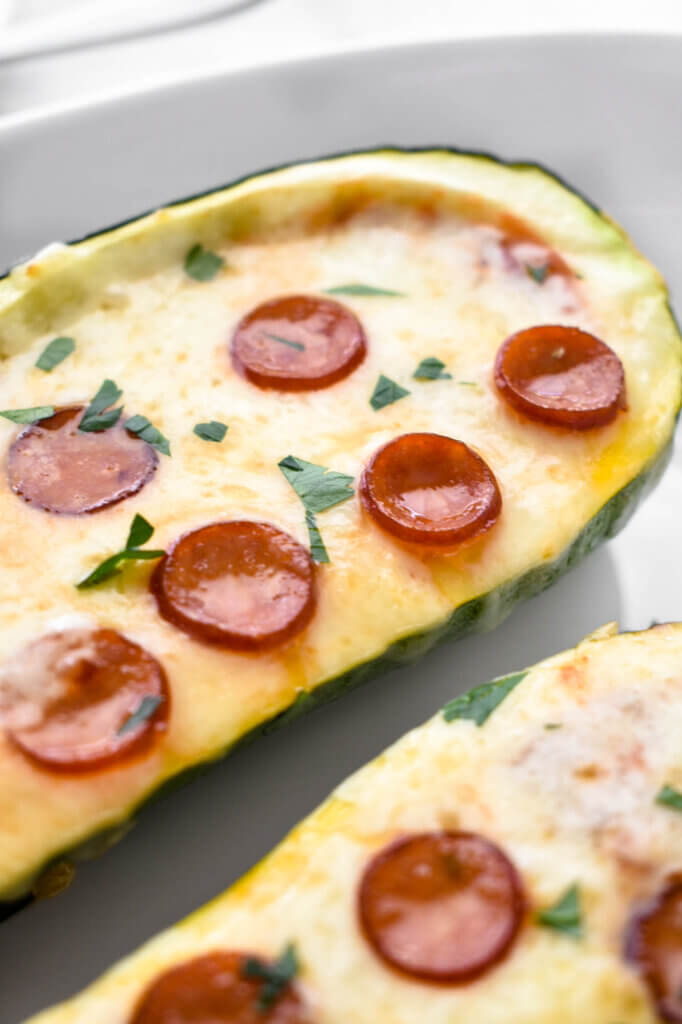 Close up of a pizza stuffed zucchini boat topped with mini pepperoni.