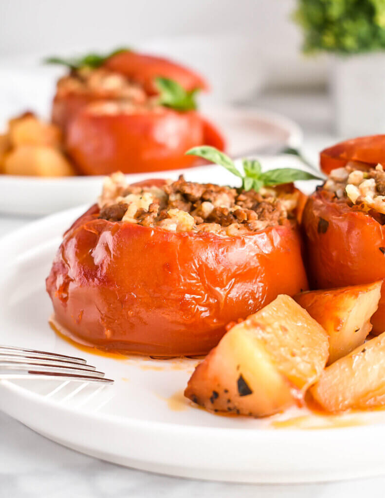 Slow Cooker stuffed tomatoes plated with potato wedges.