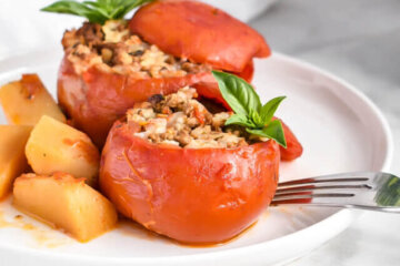 Slow Cooker Stuffed Tomatoes on a plate served with potatoes and topped with basil.