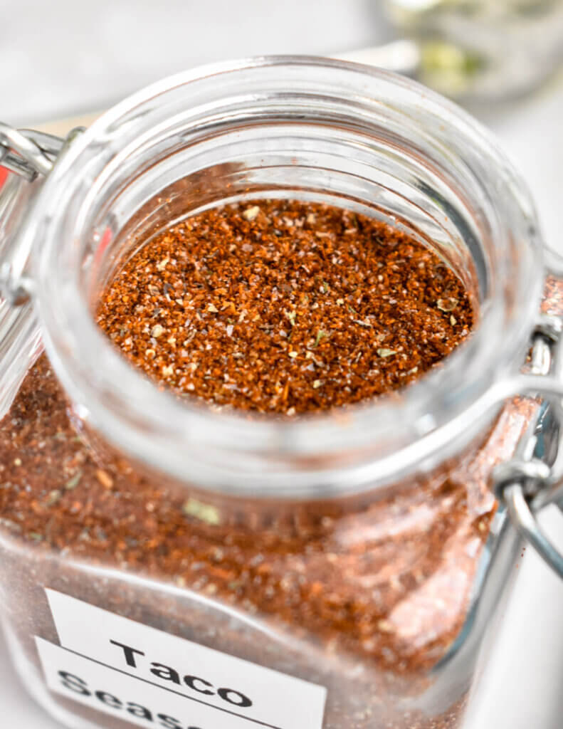 Closeup of homemade taco seasoning mix in a small glass jar.