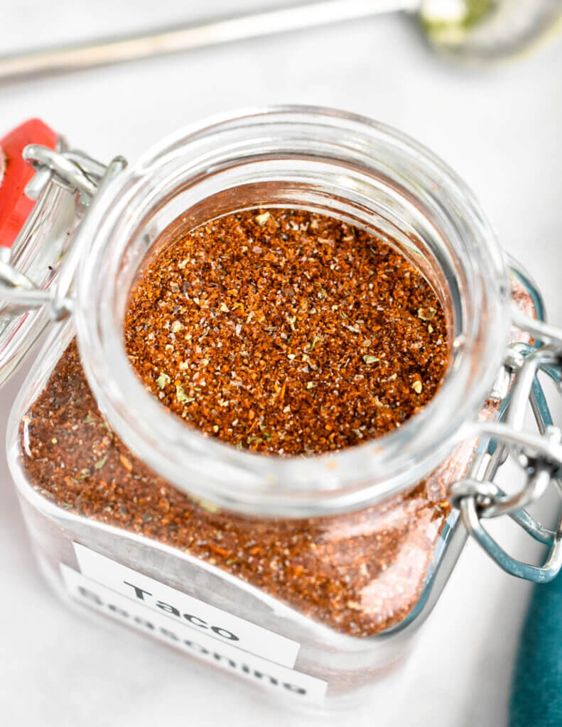 Homemade taco seasoning in a small glass spice jar labelled "Taco Seasoning".