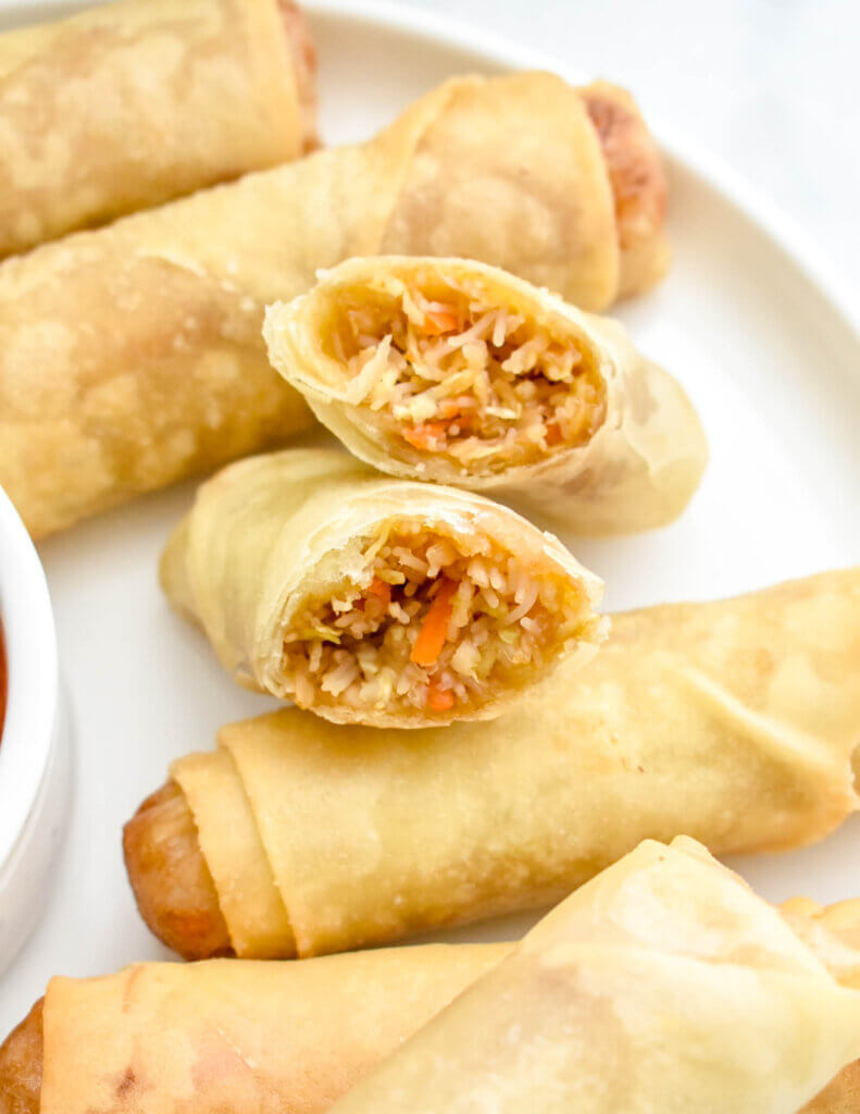 Closeup of a sliced vegetable spring roll showing the filling on a platter with other spring rolls.
