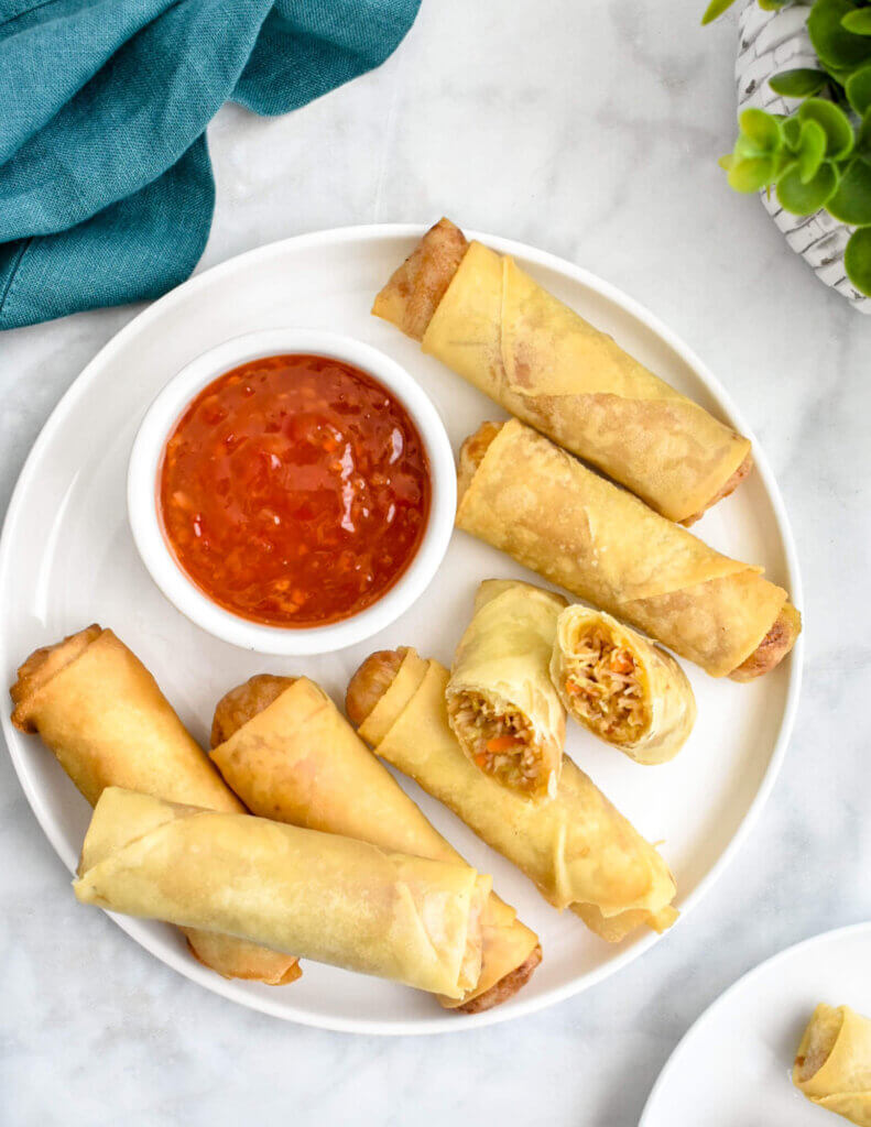 A platter of crispy vegetable spring rolls served with sweet chili sauce.