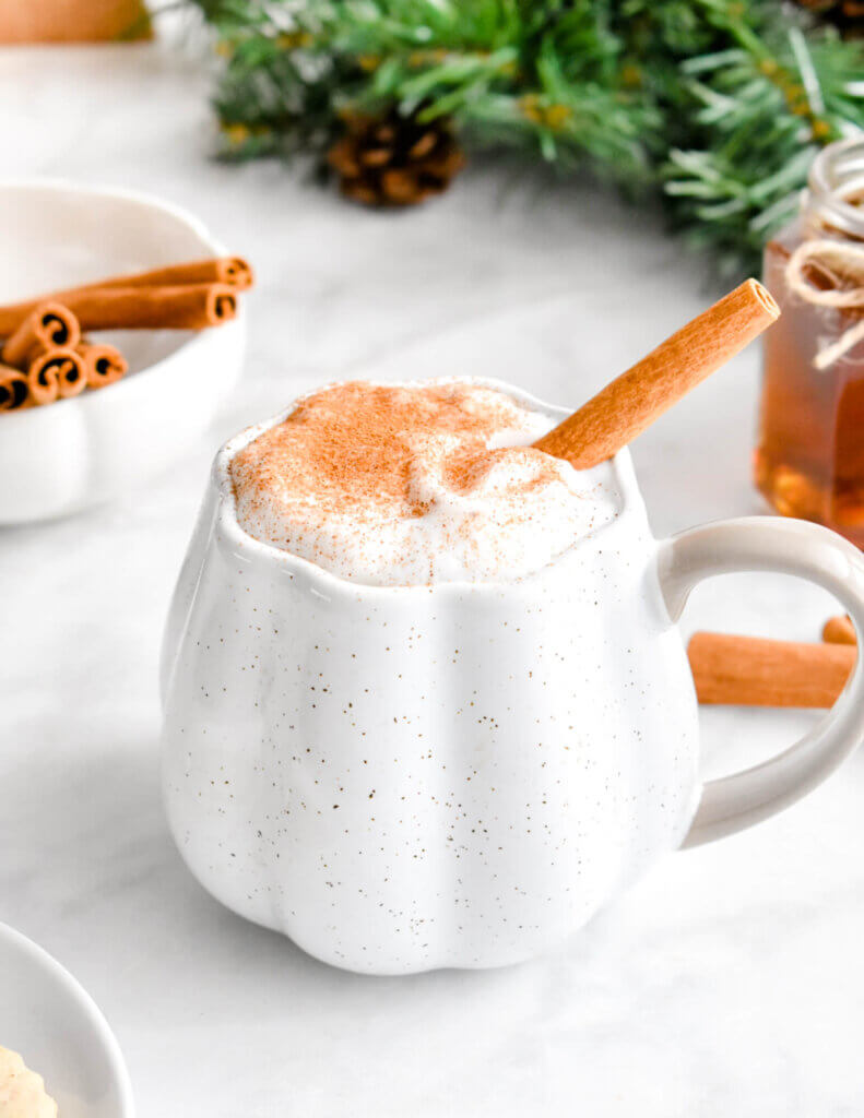 Closeup of a mug of cinnamon dolce latte garnished with sprinkled cinnamon and a cinnamon stick.