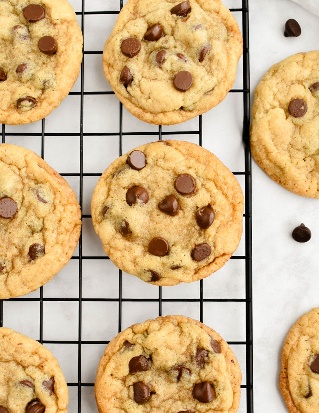 Chewy chocolate chip cookies on a black cooling rack.