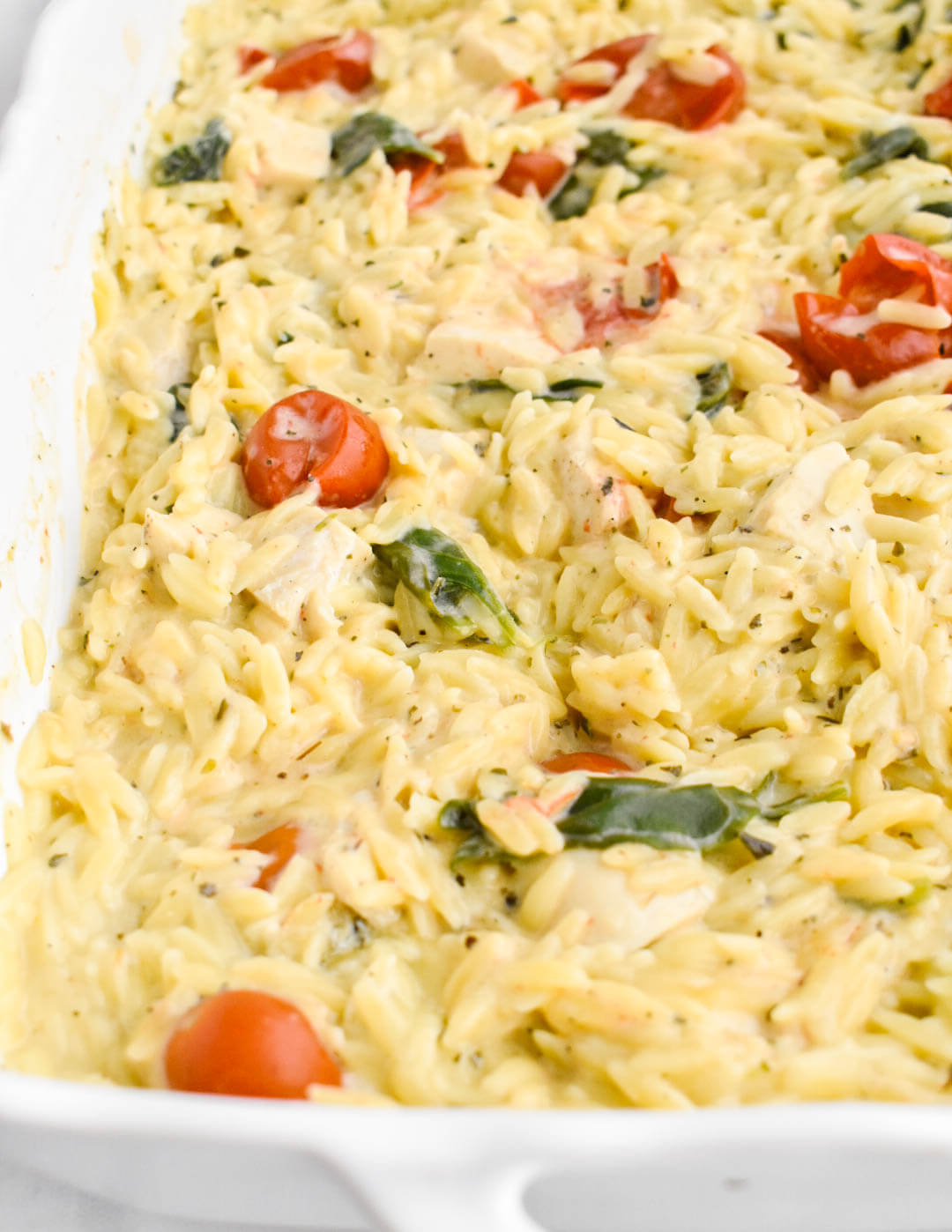 Closeup of Easy Boursin Chicken Orzo Bake in a white baking dish.