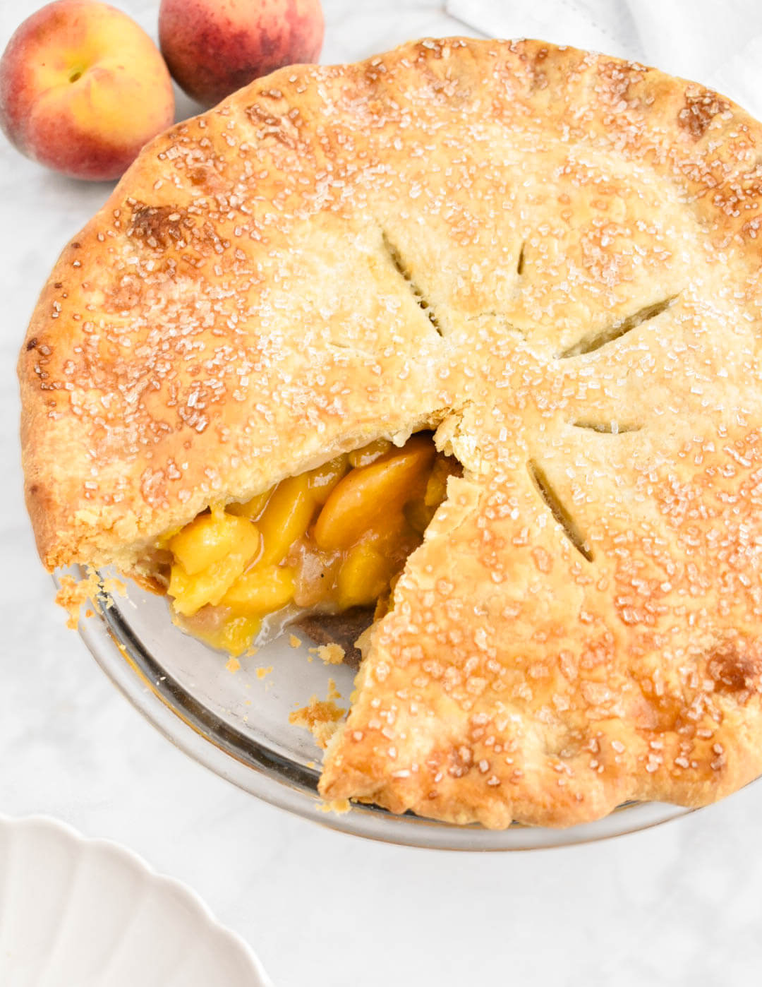 A peach pie with one slice removed, exposing the peach filling.