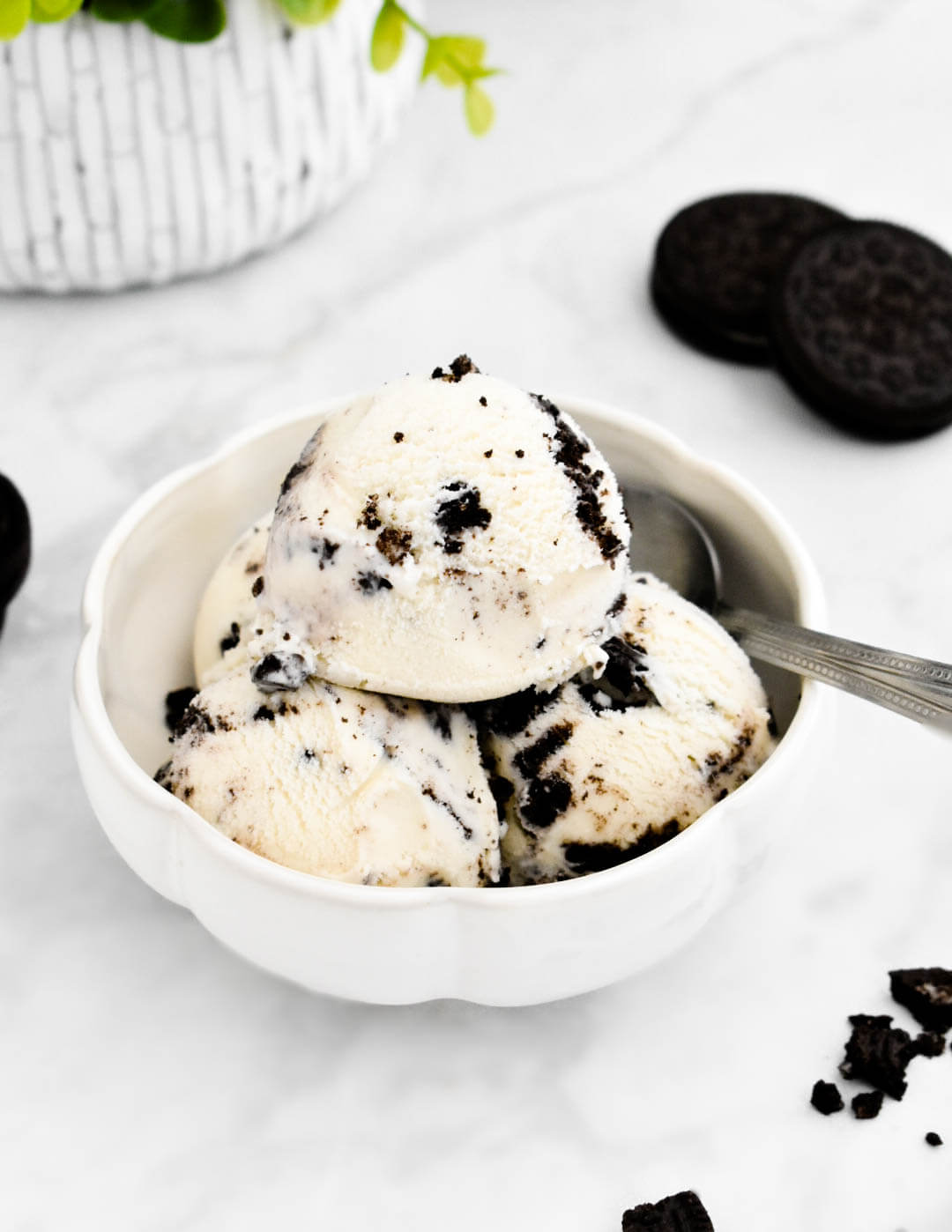 A bowl of simple Oreo ice cream set on a grey marble counter next to Oreo cookies.