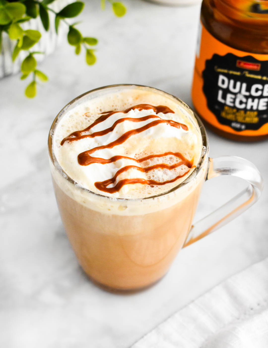 Top view of a dulce de leche latte with whipped cream and dulce de leche drizzle.
