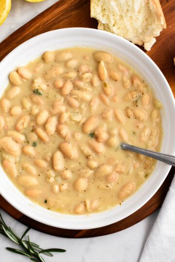 A bowl of rosemary white bean soup served with crusty bread.