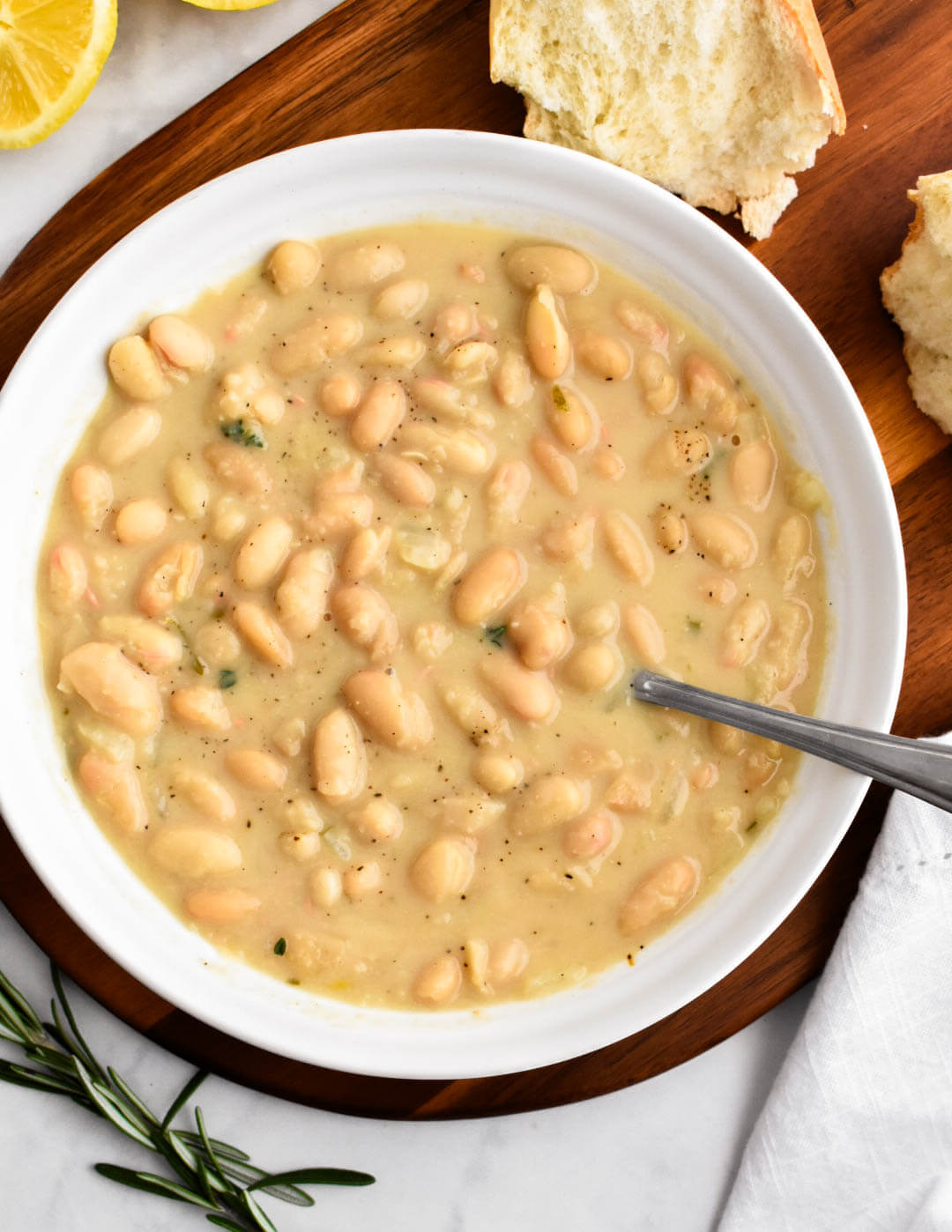 A bowl of rosemary white bean soup served with crusty bread.