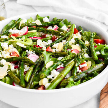 Asparagus Salad made with salad greens, sauteed asparagus, cherry tomatoes, radishes, feta cheese, and almond slivers drizzled with lemon herb vinaigrette.