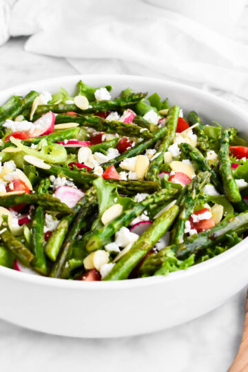 Asparagus Salad made with salad greens, sauteed asparagus, cherry tomatoes, radishes, feta cheese, and almond slivers drizzled with lemon herb vinaigrette.