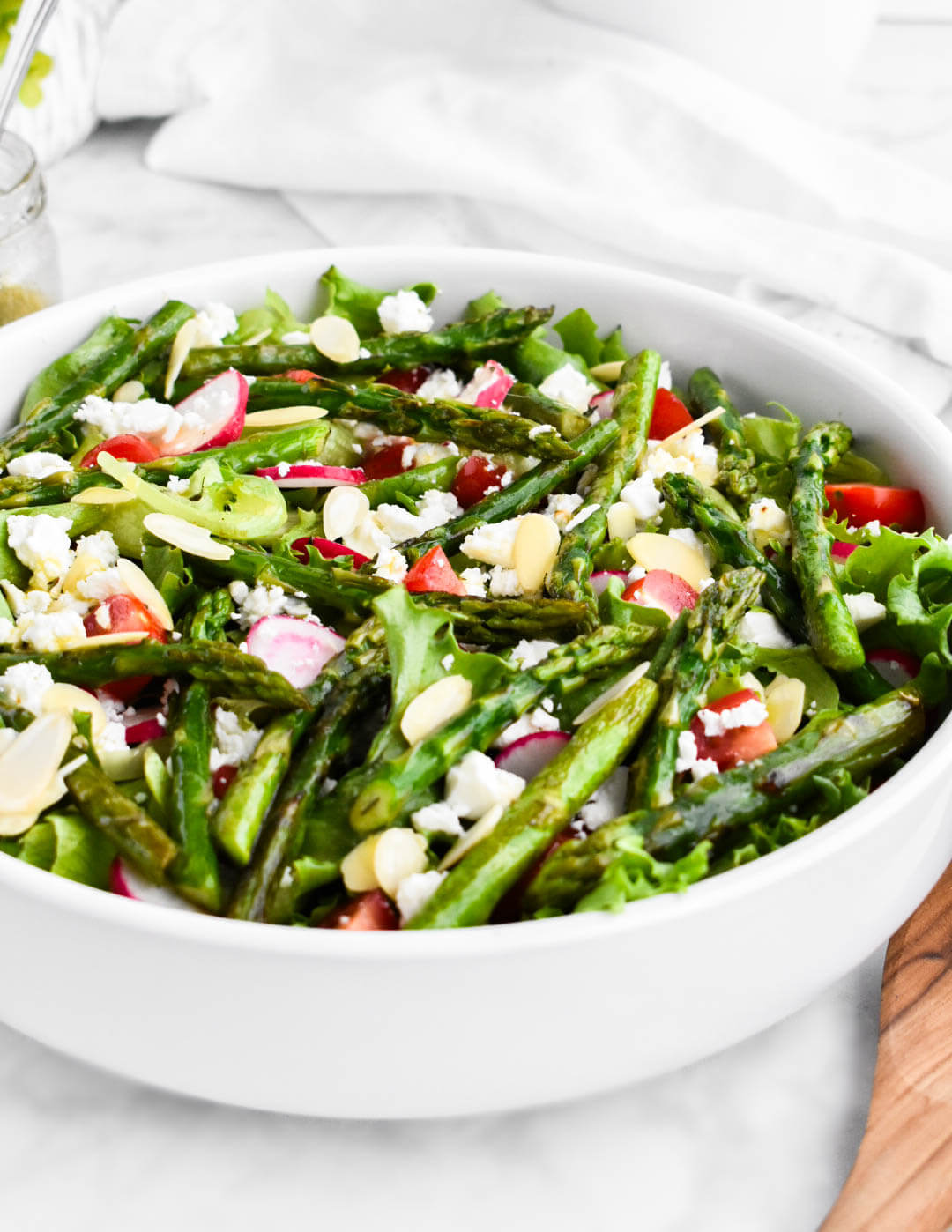 Asparagus Salad made with salad greens, sauteed asparagus, cherry tomatoes, radishes, feta cheese, and almond slivers drizzled with lemon herb vinaigrette.