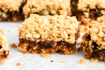 Sliced date square on parchment paper showing the layers of crust and filling.