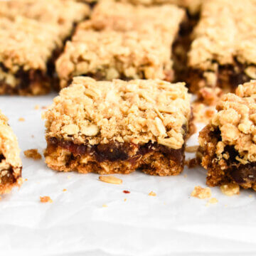 Sliced date square on parchment paper showing the layers of crust and filling.