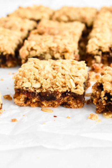 Sliced date square on parchment paper showing the layers of crust and filling.
