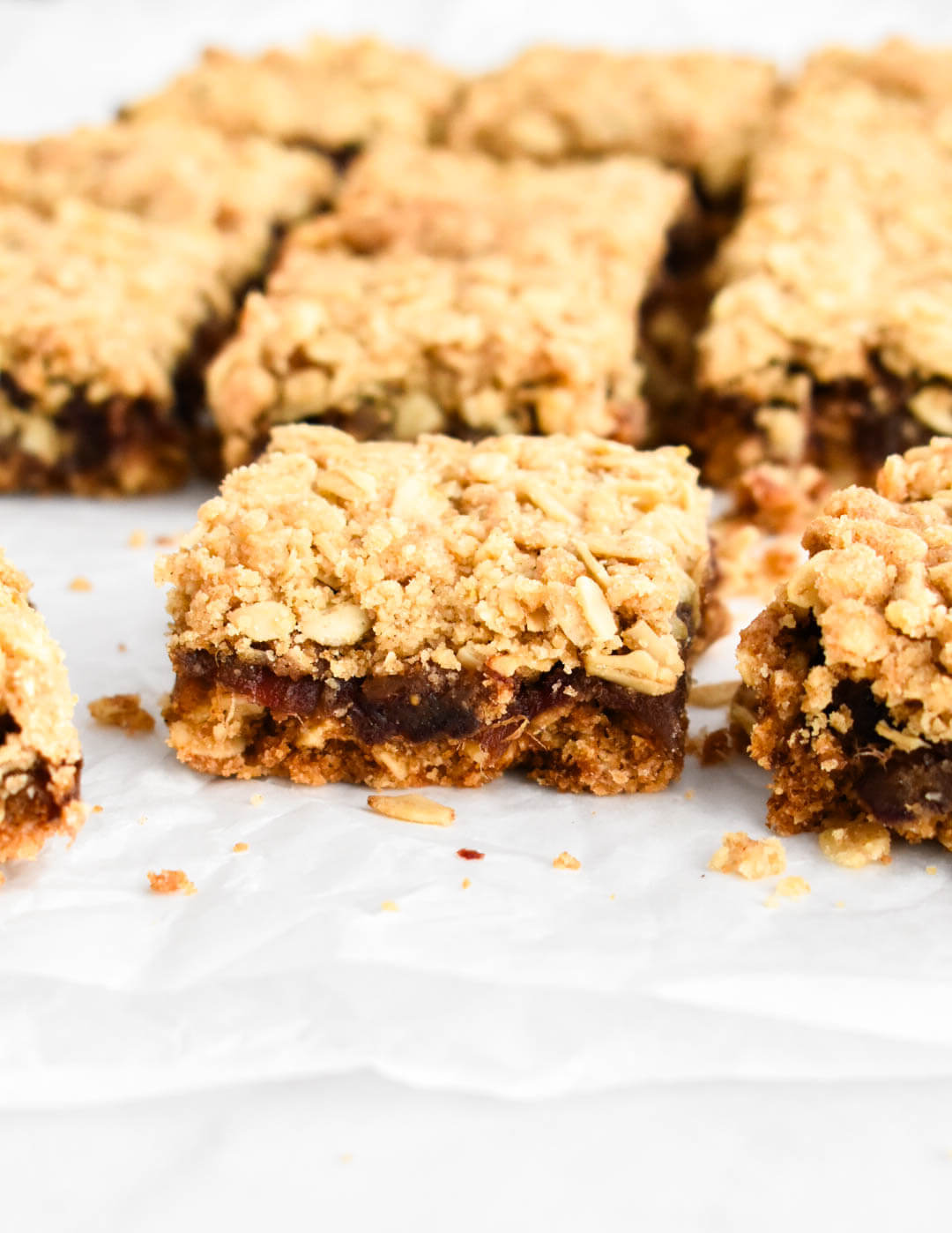 Sliced date square on parchment paper showing the layers of crust and filling.
