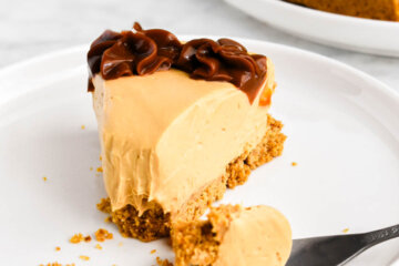 A slice of dulce de leche cheesecake with a forkful of cheesecake broken away.