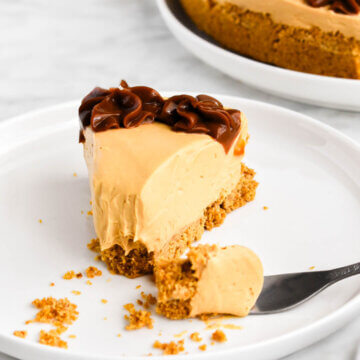 A slice of dulce de leche cheesecake with a forkful of cheesecake broken away.