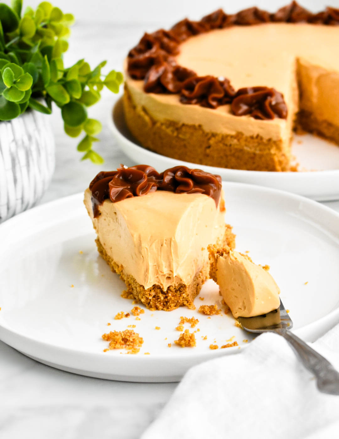A slice of dulce de leche cheesecake with a bite of cheesecake on a fork.